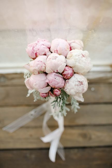 Close-up photo of a pink and white peony bridal bouquet on rustic wood.