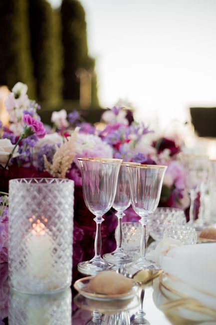 Luxe outdoor wedding table setting with floral decorations and glassware, exuding elegance and romance.