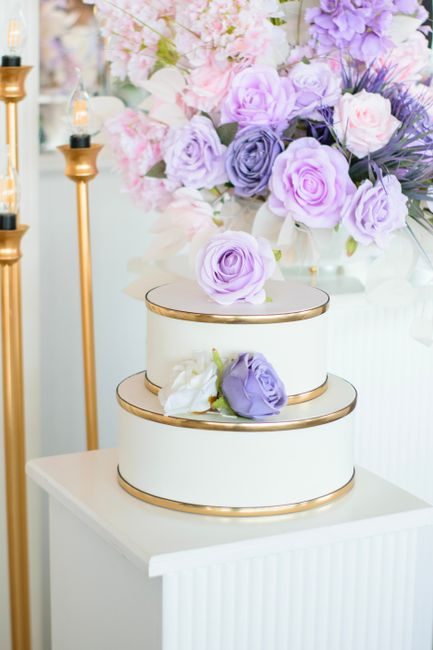 A sophisticated wedding cake adorned with purple and white roses, perfect for elegant celebrations.