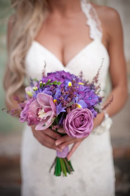 Close-up of a bride holding a purple and white floral bouquet, perfect for wedding themes.