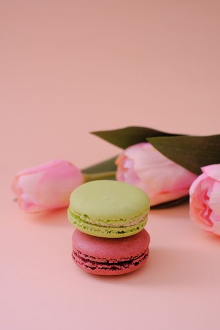 A charming arrangement of pastel macarons and pink tulips perfect for a spring dessert setup.
