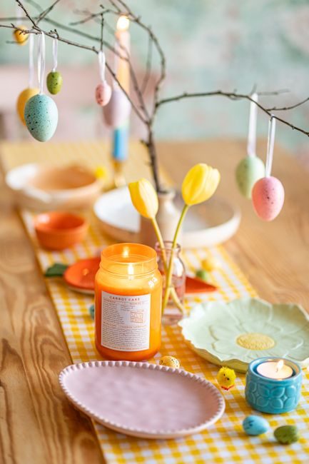 Festive Easter table arrangement with candles, tulips, and decorative eggs.