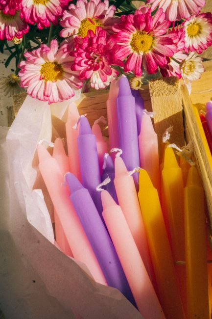 A close-up of colorful candles and fresh pink flowers in a cozy arrangement.