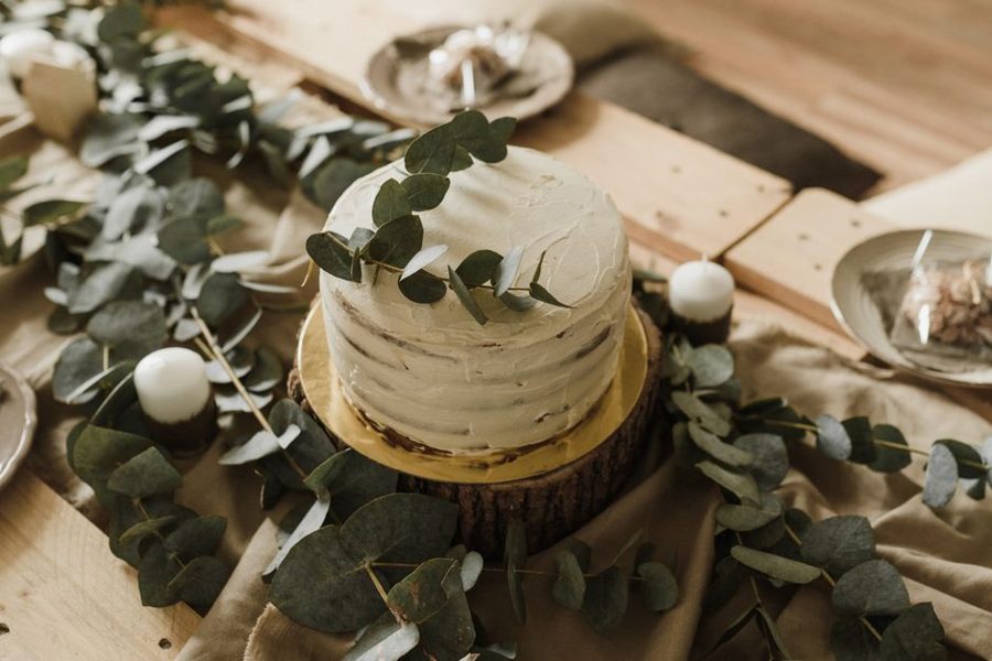 Elegant rustic cake on wooden table with eucalyptus, perfect for weddings or celebrations.