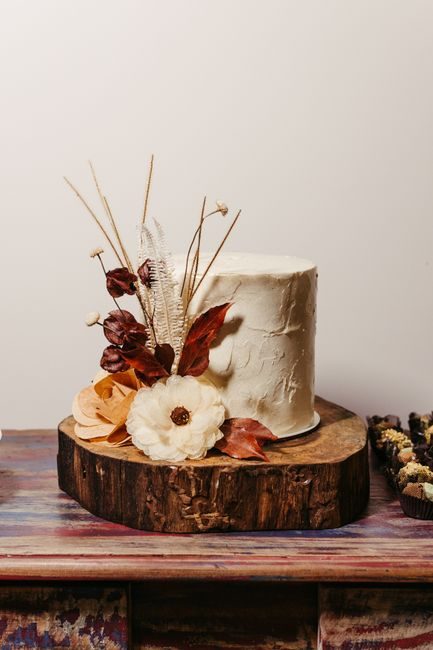 Elegant rustic cake adorned with dried flowers on wooden base, perfect for weddings.