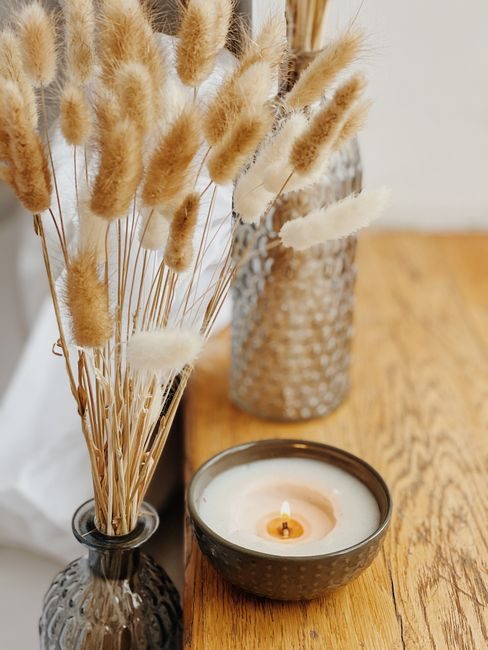 Warm and inviting setting with pampas grass and candle on a wooden table.