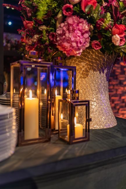 Close-up of an elegant floral arrangement with lit candles in glass holders, perfect for a romantic setting.