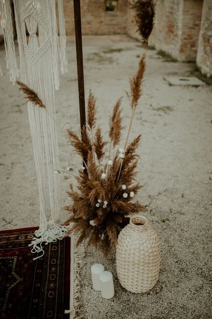 Elegant boho wedding setup featuring pampas grass, woven decorations, and candles.