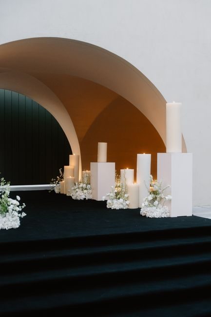 A beautifully decorated wedding arch with white candles and floral arrangements, perfect for a modern ceremony.