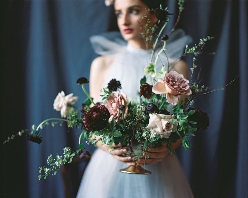 A bride holding a lush flower bouquet, showcasing elegance and contemplation.