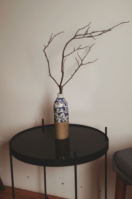 Artistic display of a decorative vase with twigs on a modern round table.