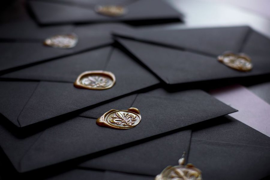 Close-up of stylish black envelopes featuring vintage wax seals, perfect for luxury invitations.