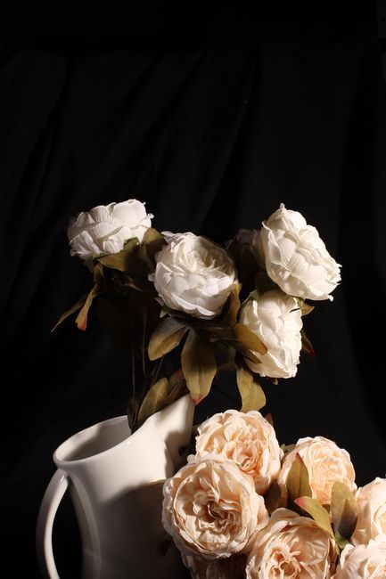 White roses elegantly arranged in a classic ceramic vase against a dark background.